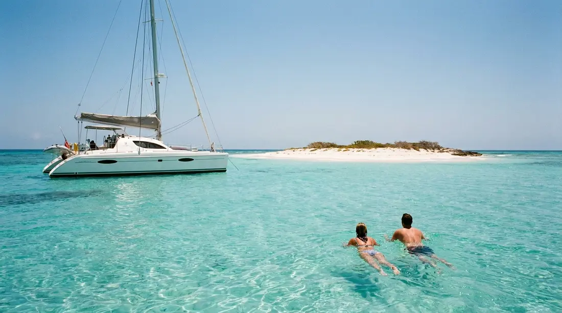 A catamaran anchored off a white-sand cay