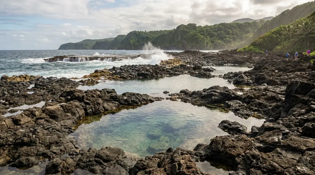 Clear tide pools in dark rock with surf breaking beyond