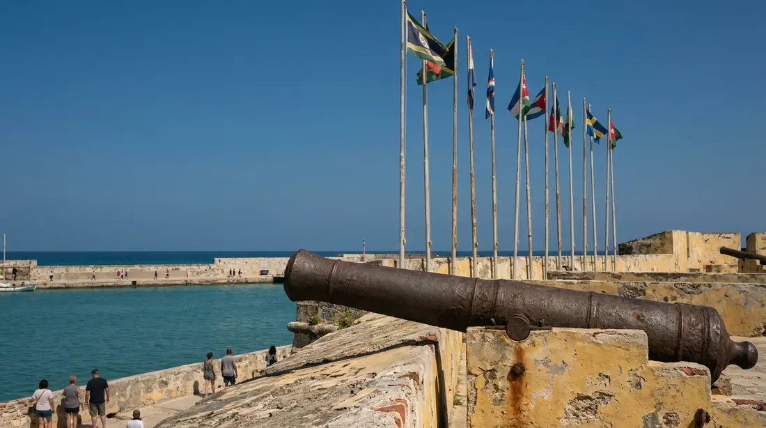 A cannon on a fort rampart above a turquoise harbor