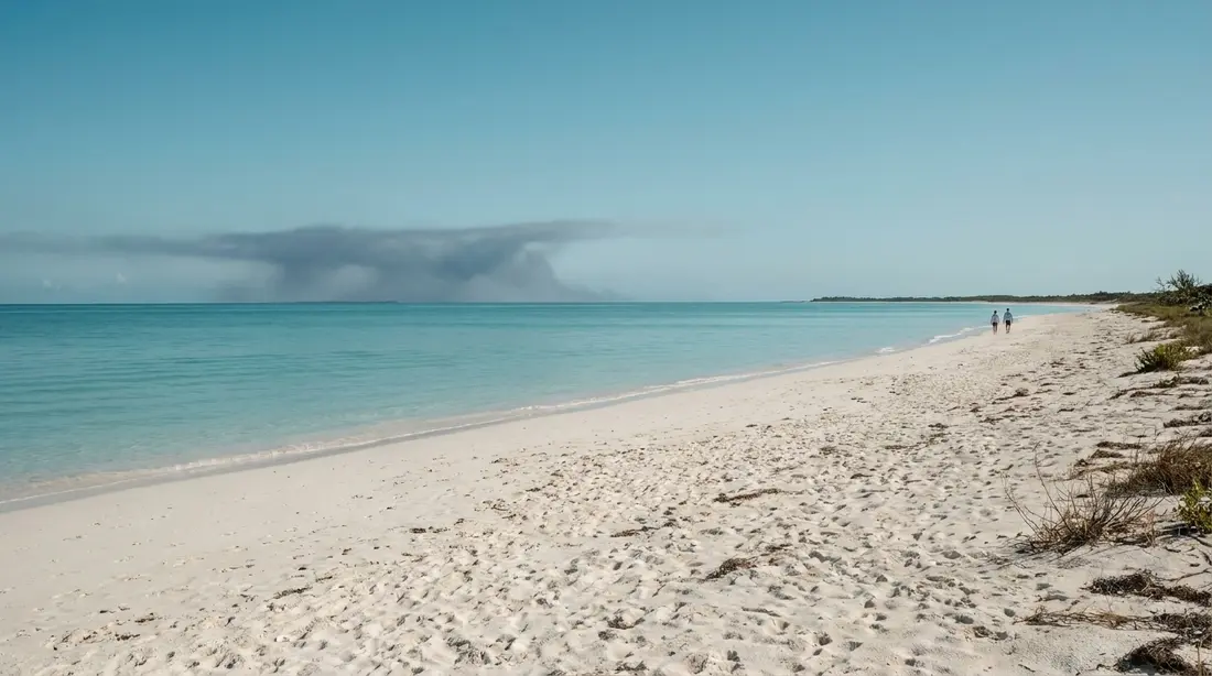 An empty beach with a distant rain squall at sea