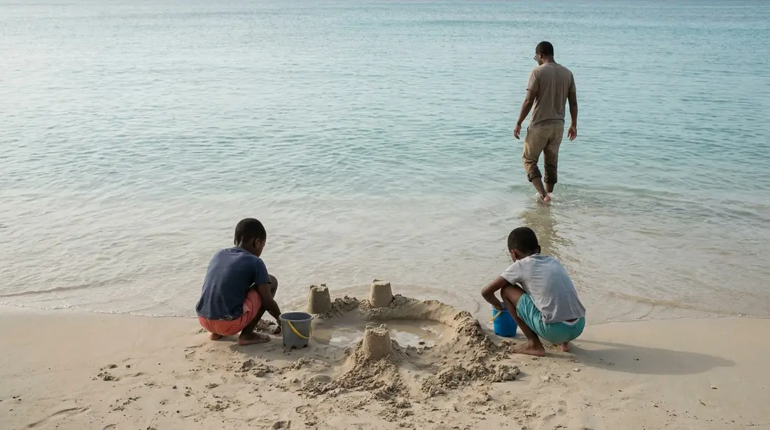 Children building a sandcastle beside calm shallow water