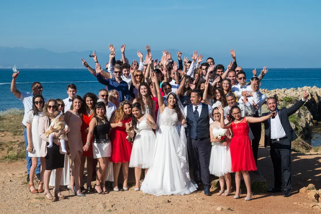 A wedding party gathered on the sand by the sea